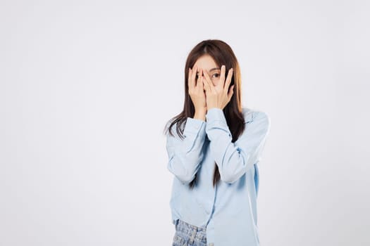 Woman hides in fear, afraid woman covers her face using both hands, reacting to something scary with expressive eyes, on a clean white studio isolated background.