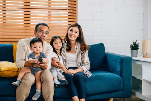 A modern family with kids shares happiness and togetherness watching TV movies in the living room. The father mother son and daughter create cherished family moments filled with laughter and fun.