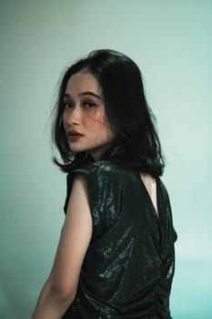 Asian Model posing with touching her black hair and feeling sexy and hot while wearing a black dress