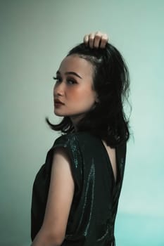 Asian Model posing with touching her black hair and feeling sexy and hot while wearing a black dress