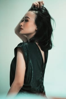Asian women playing her black hair while wearing black dresses with smiling faces with green background