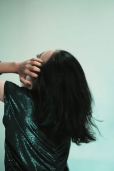 Asian women playing her black hair while wearing black dresses with smiling faces with green background