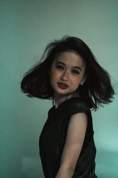 Asian women playing her black hair while wearing black dresses with smiling faces with green background