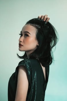 Asian Model posing with touching her black hair and feeling sexy and hot while wearing a black dress