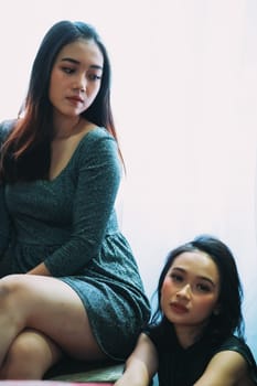 Two Sexy women wearing a short dress and sitting together with sensual faces and feeling horny and hot