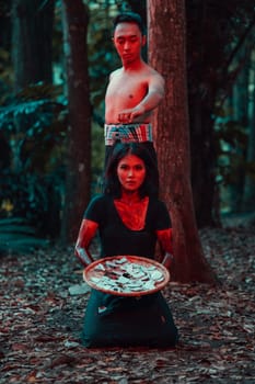 a couple of serial killers have bodies covered in blood and are performing a satanic ritual in the middle of a forest before sunset