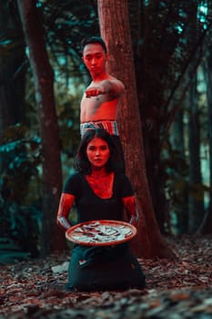 a couple of serial killers have bodies covered in blood and are performing a satanic ritual in the middle of a forest before sunset