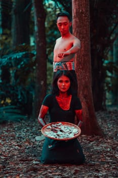 a couple of serial killers have bodies covered in blood and are performing a satanic ritual in the middle of a forest before sunset