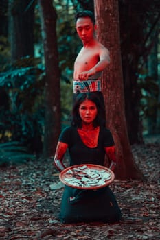 a couple of serial killers have bodies covered in blood and are performing a satanic ritual in the middle of a forest before sunset