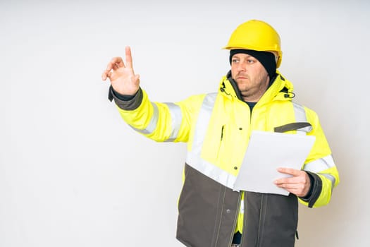 a man in a yellow working winter jacket, yellow safety helmet with papers in his hands. High quality photo