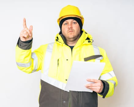 a man in a yellow working winter jacket, yellow safety helmet with papers in his hands. High quality photo
