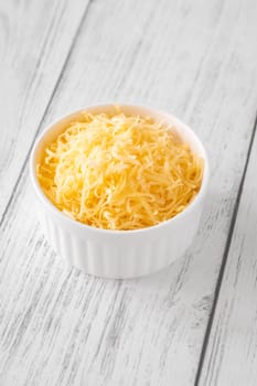 Bright shredded cheddar cheese in white bowl, perfect for topping or melting