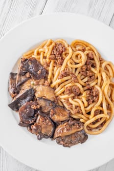 White plate of thick udon with beef, and mushroom topping