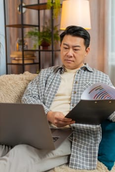 Stressed man freelancer feeling worried about financial problem doing paperwork sitting on sofa in living room. Tired Middle Eastern male frustrated thinking of money debt, budget loss, bankruptcy.