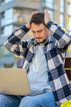 Sad mature man tourist using laptop computer typing browsing, loses becoming surprised sudden lottery results, bad news, fortune loss, fail. Angry guy sitting on bench downtown. Town lifestyles.