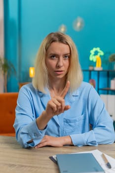 Portrait of Caucasian young business woman shakes finger, saying No be careful scolding and giving advice to avoid danger mistake disapproval sign at office. Confident freelancer girl at desk at home.