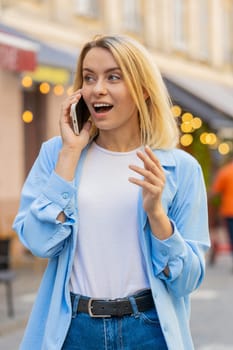 Caucasian woman tourist having remote conversation communicate speaking by smartphone with friend, talking on phone unexpected good news gossip walking on urban city street. Town lifestyles outdoors