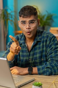 Displeased upset Indian man reacting to unpleasant awful idea, dissatisfied with bad quality, wave hand, shake finger No, dismiss idea, don't like proposal. Hispanic guy at home office table. Vertical