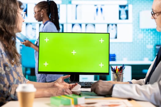 Medic and woman patient discuss about a new treatment plan next to green screen, reviewing the hospital records to ensure recovery. Doctor meeting with client at the check up visit in office.