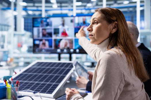Solar panels factory investors evaluate investment profitability during teleconference meeting. Photovoltaics plant executives analyzing green energy manufacturing machinery during internet videocall