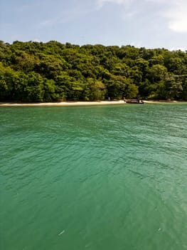 Drone shot of tropical sailboats in a turquoise bay near the harbor, boats floating in crystal clear water near a scenic Thai island with rocky beach. Picturesque shoreline with fun activities.