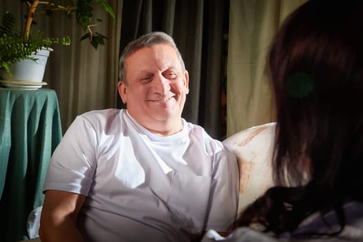 A middle-aged couple captures their love in a warm indoor setting, posing together with smiles in their comfortable apartment.