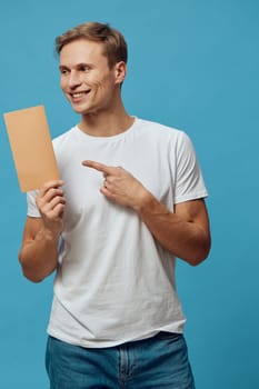 smiling man pointing blank card wear white tshirt casual look isolated blue background young caucasian male holding empty cardboard workspace communication digital nomad concept