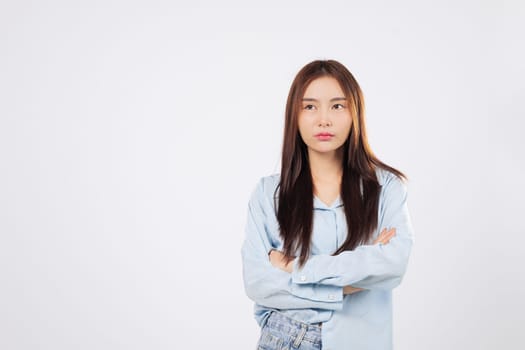 Unhappy and angry, Asian woman raises a clenched fist as second woman stands with crossed arms, shouting loudly in a studio with isolated clean white copy space.