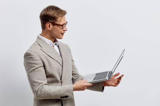 young caucasian man working laptop wearing beige jacket and glasses looking at screen with concentration isolated on plain background remote freelance digital nomad concept of online work lifestyle
