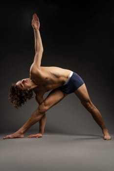 Full body side view of slim barefoot female in sportswear standing on tiptoes with raised arms while practicing yoga in studio