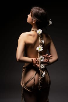 Gentle bdsm with flowers - Back view of anonymous topless female model tied up with ropes with white flowers