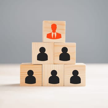 A red manager icon stands out prominently from a group of staff employee icons printed on a wooden block, representing the concept of different thinking and human development within a business setting