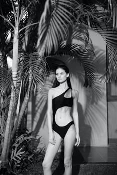 Tropical Paradise Woman in Black One Piece Swimsuit Standing Among Palm Trees Against a Black and White Background