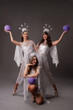 Full body of young bride in white dress and veil holding blue balloon in hands and looking at camera against gray background