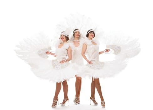 Full body of content female dancers in white art deco costumes with headband looking at camera with feather fans against white background
