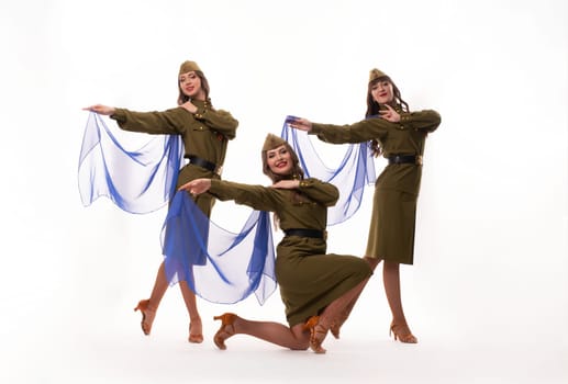 Full body of happy young female friends in trendy outfits smiling and looking at camera while dancing against white background
