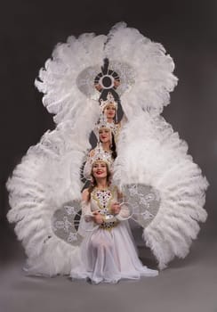 Full body side view of elegant bride in white dress and veil with bouquet of white flowers on black background