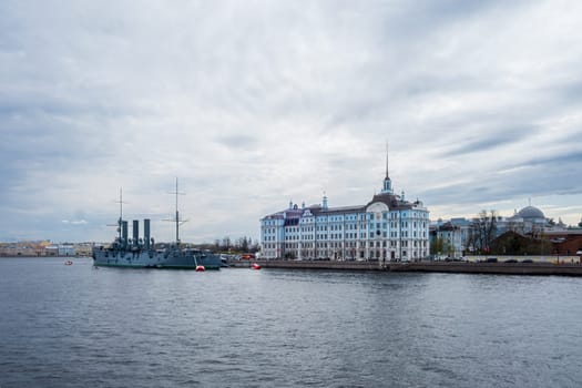 Saint Petersburg, Russia - 02.05.25. Cruiser Aurora moored near Nakhimov Naval school on the Neva River in St. Petersburg. Iconic landmarks represent Russia's maritime heritage and educational legacy.