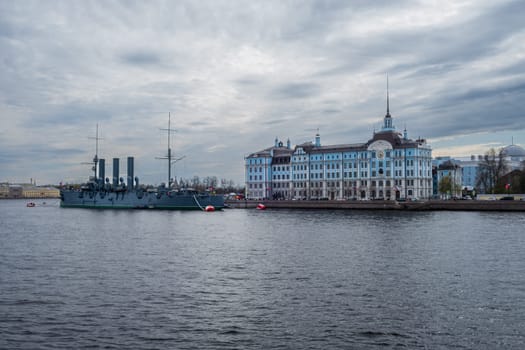 Saint Petersburg, Russia - 02.05.25. Cruiser Aurora moored near Nakhimov Naval school on the Neva River in St. Petersburg. Iconic landmarks represent Russia's maritime heritage and educational legacy.