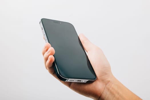A hand holding a black cell phone isolated on white background, Man hand holding black smartphone mockup blank screen display, web site design application