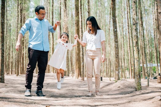 Full length portrait Asian family enjoying a peaceful walk through park forest outdoor holding hands spending time together on weekend, Happy father mother and daughter, Family day memory on holiday