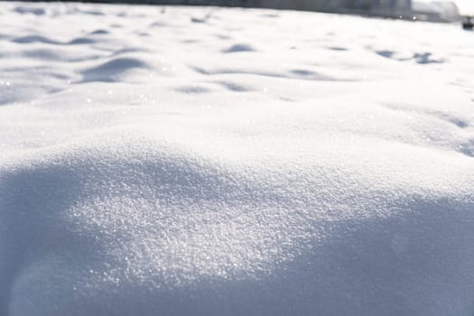 Textured snow mounds sparkling in daylight, forming natural curves and subtle shadow play. Clean, untouched surface evokes calmness and purity of winter nature.