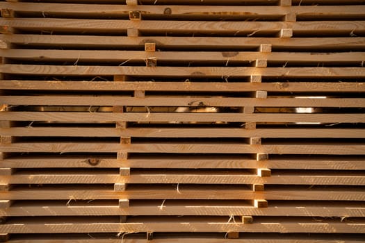 Neatly arranged wood planks stacked horizontally, highlighted by afternoon light casting dramatic shadows across the surfaces and textures of freshly sawn timber.