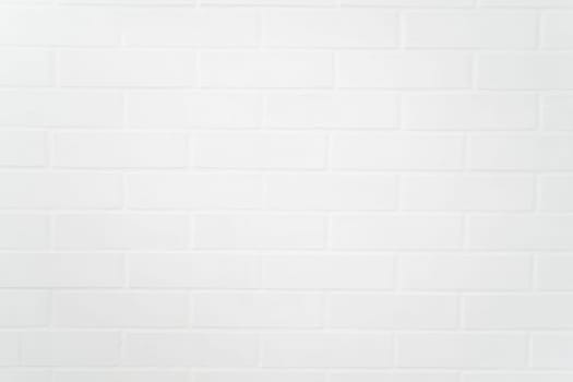 Flat closeup of white painted brick wall texture, showcasing uniform pattern, grout lines, and matte finish ideal for backgrounds or architectural design use.