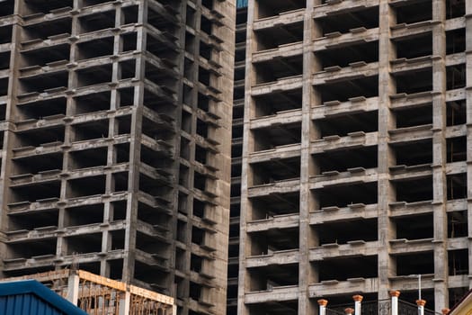 Densely framed shot of two unfinished concrete towers, focusing on depth, repetition, and shadow play between structural elements of modern construction.