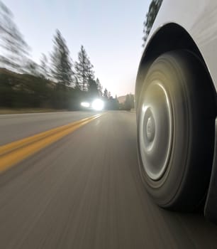 A car is speeding down a road with a bright light shining on the tire. Concept of excitement and adrenaline as the car races down the road