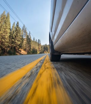A car is driving down a road with yellow lines. The car is white and is in the middle of the road