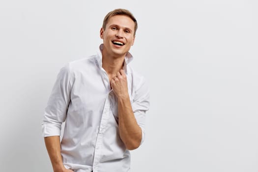 Happy smiling man in white shirt with rolled-up sleeves looking joyful against a plain gray background. Confident and relaxed expression, casual attire, middle-aged male model, positive energy, studio shot, lifestyle concept.