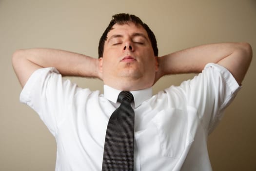 A man in a white shirt and black tie is relaxing with his arms behind his back. Concept of calm and relaxation, as the man is taking a break from his busy day