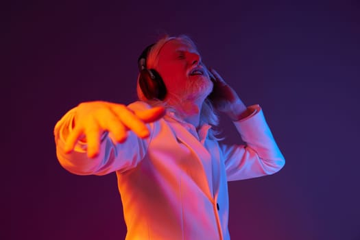 elderly man in a white jacket, immersed in music while wearing headphones, vibrant purple and orange background enhances the dynamic mood, showcasing joy and rhythm through expressive body language